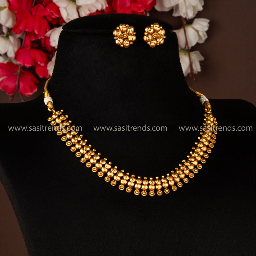 Traditional antique gold plated brass jewellery set with necklace and earrings against a dark background