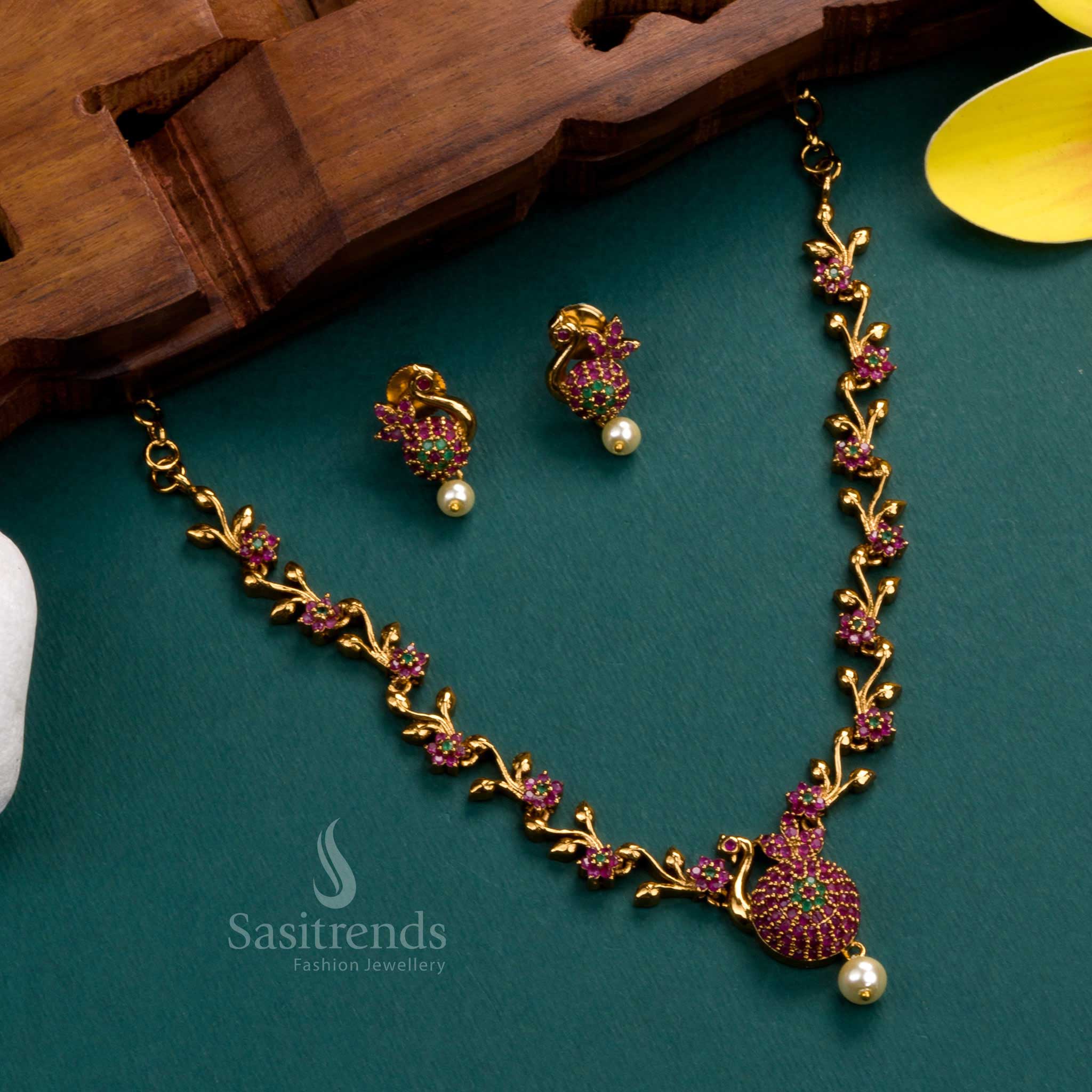 Magnificent matte gold-plated jewellery set featuring an intricate peacock feather design, embellished with vibrant ruby-green American diamond stones - Sasitrends