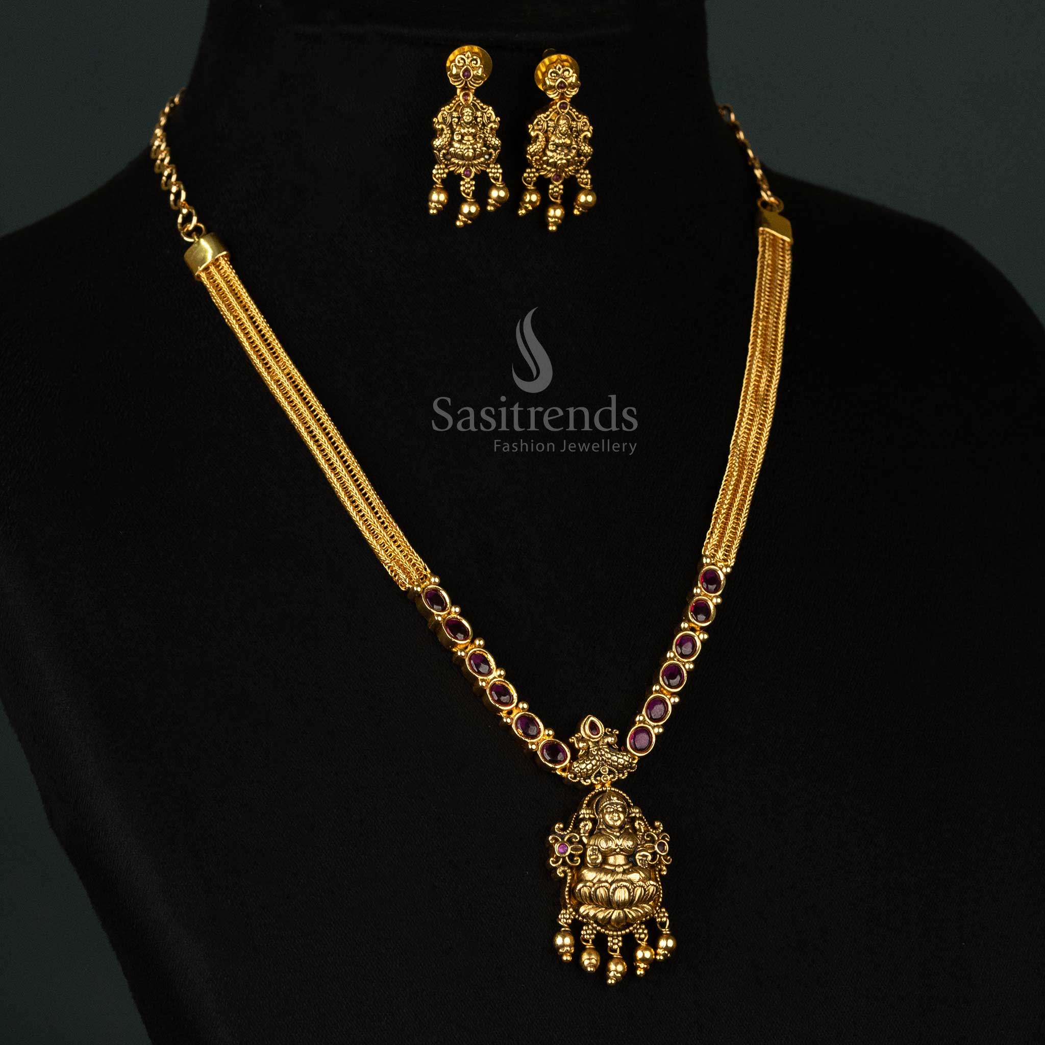 Magnificent matte gold plated temple necklace set featuring a divine Goddess Lakshmi pendant, intricate dual peacock motif, and radiant ruby AD stones - Sasitrends