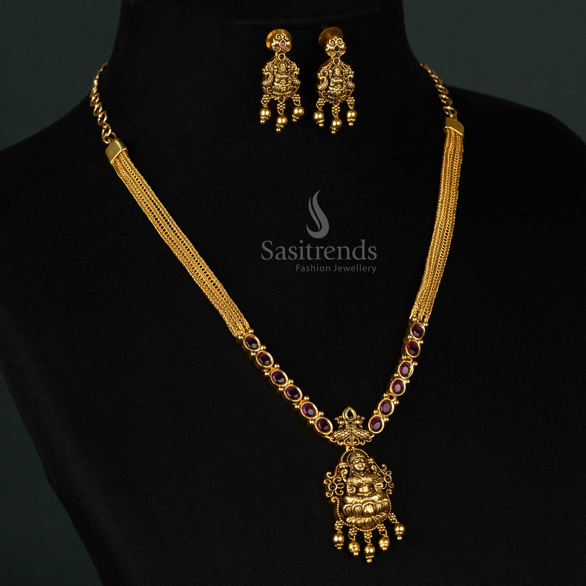 Regal temple-style matte gold plated necklace set with an ornate Goddess Lakshmi pendant, elegant peacock artwork, and striking ruby-green stone embellishments - Sasitrends