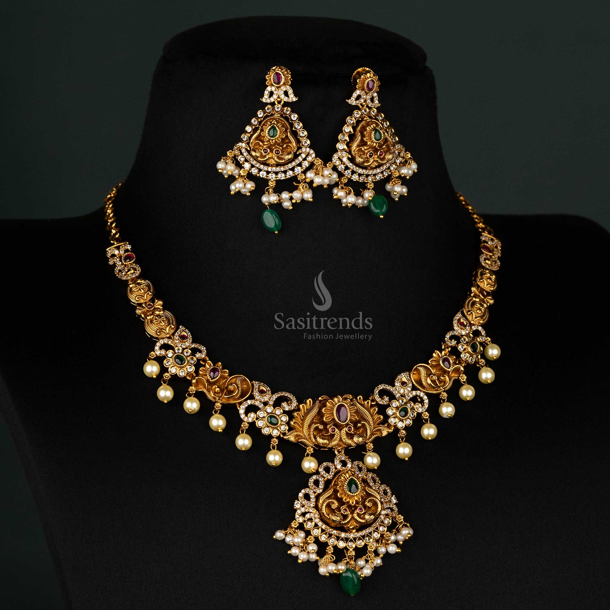 Luxurious matte gold temple jewellery necklace set with ruby and green stones, intricate peacock design, and cascading pearls - Sasitrends