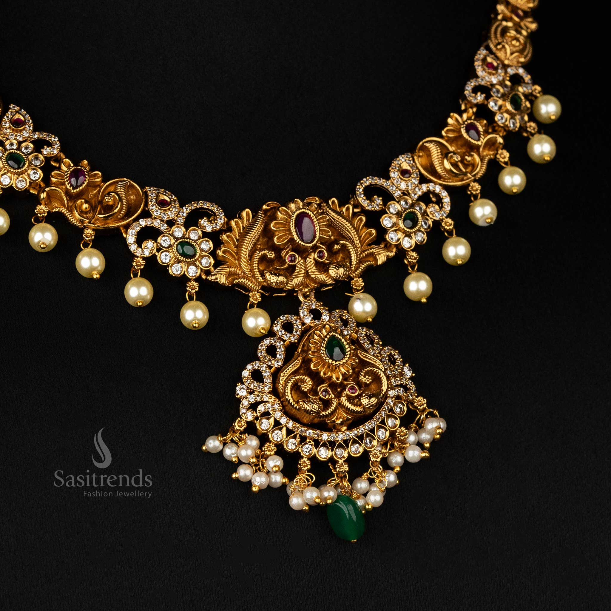 Opulent premium temple jewellery set with ruby and green stones, matte gold plating, and cascading pearls in a peacock-inspired design - Sasitrends