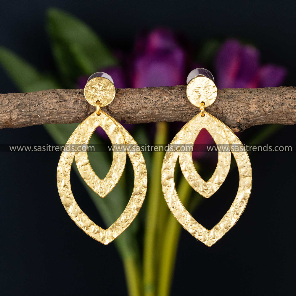 Double teardrop design gold-plated earrings against a floral backdrop