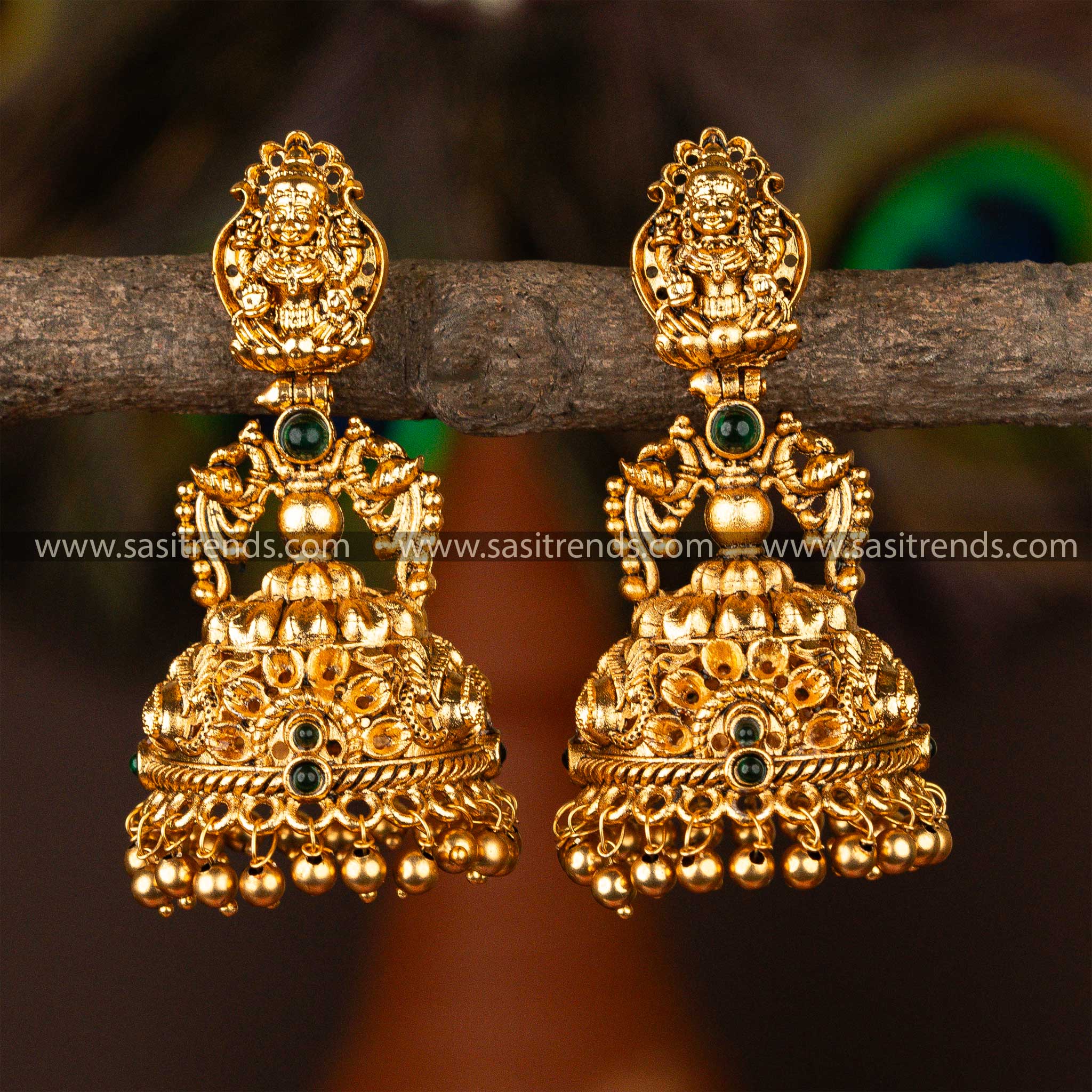 Exquisite bridal temple jhumka earrings with Lakshmi engravings and radiant ruby gems, epitomizing Indian cultural elegance.