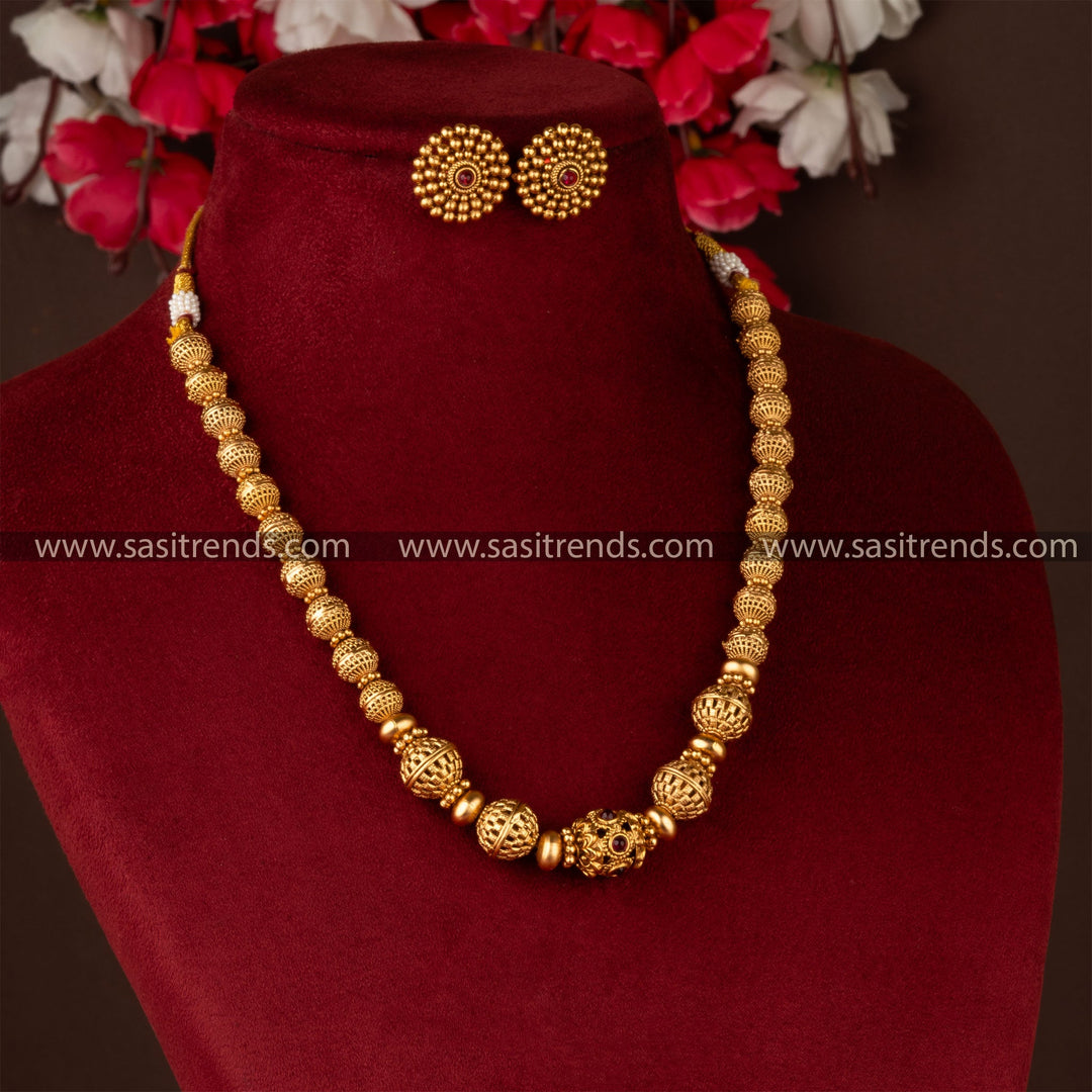 Traditional gold-plated beaded brass necklace and earrings on burgundy display