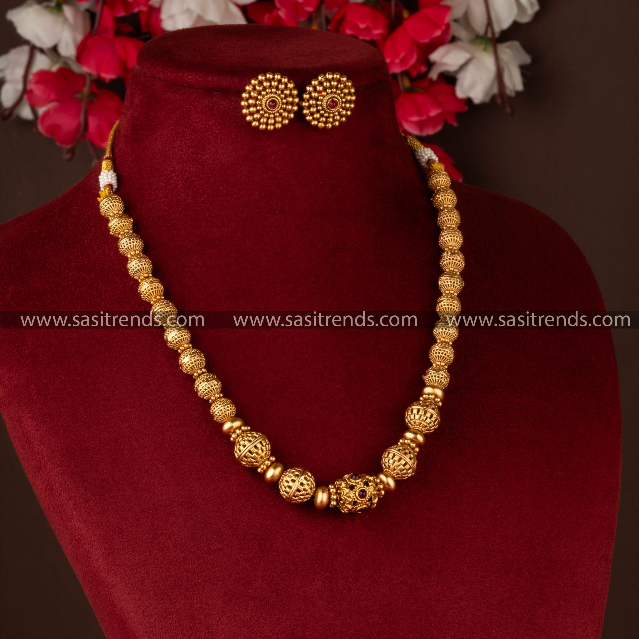 Traditional gold-plated beaded brass necklace and earrings on burgundy display