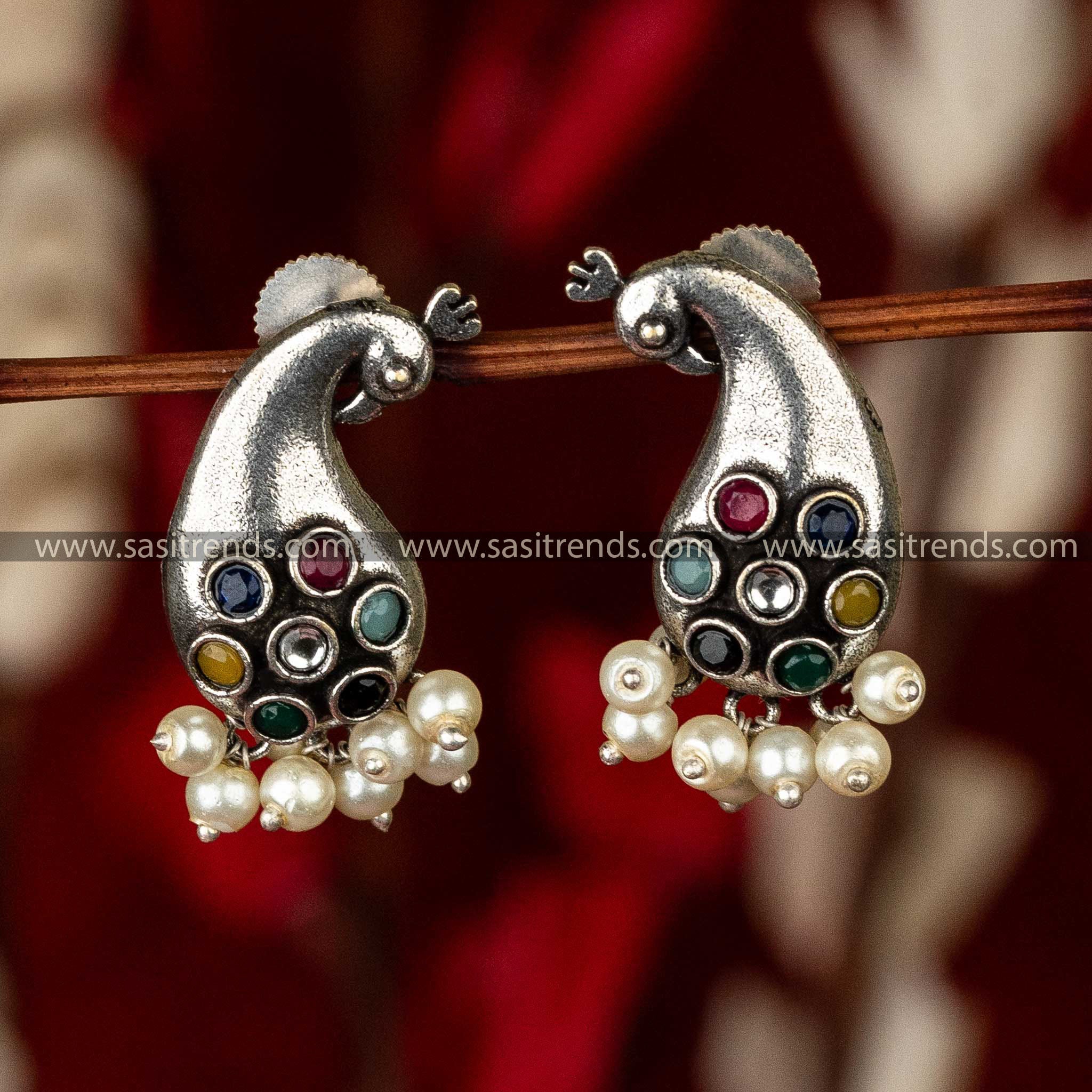 Multicolored stone peacock earrings with pearls, oxidized finish on a red surface