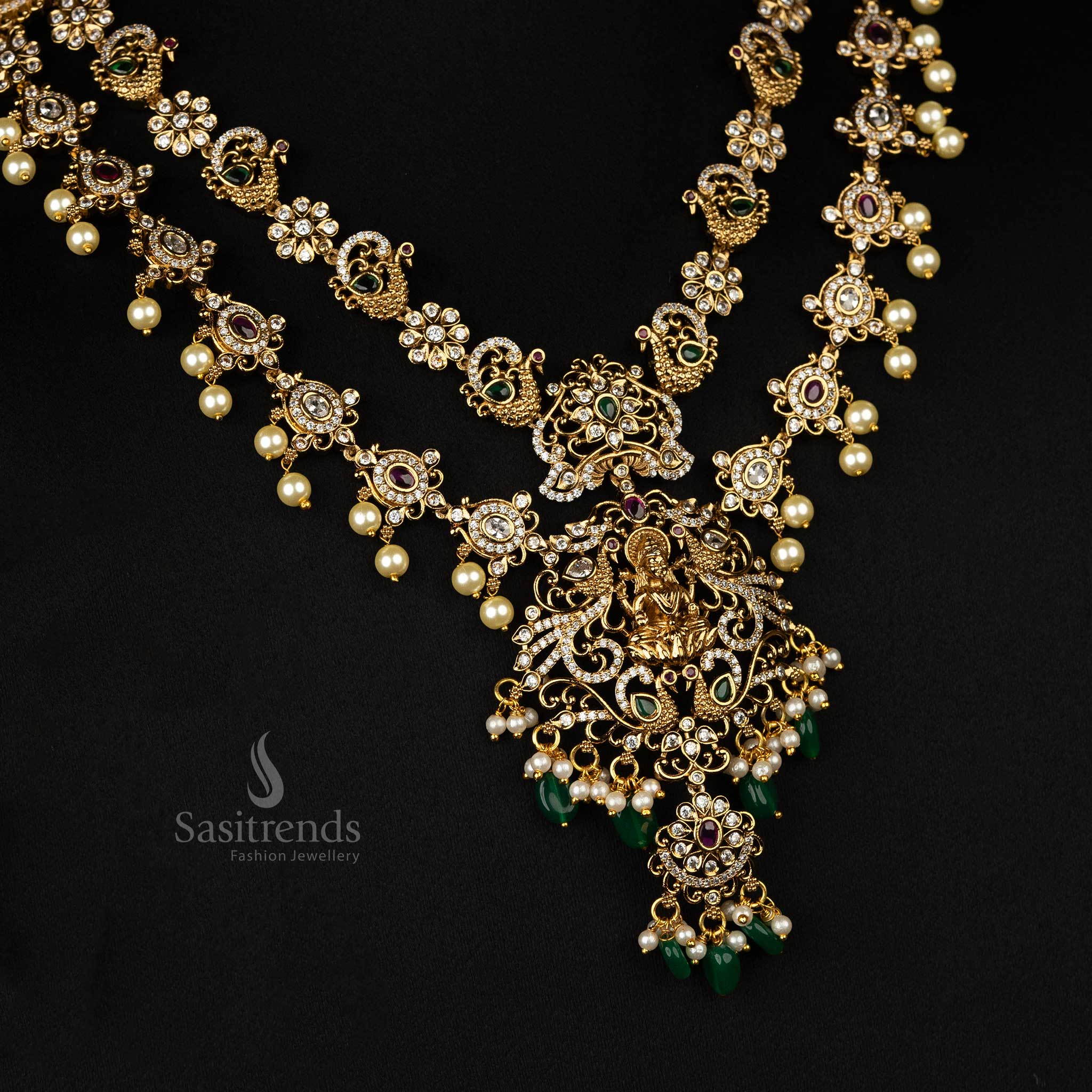 Exquisite temple-style two-line jewellery set with a matte gold finish, Lakshmi motifs, peacock designs, and dangling pearls - Sasitrends