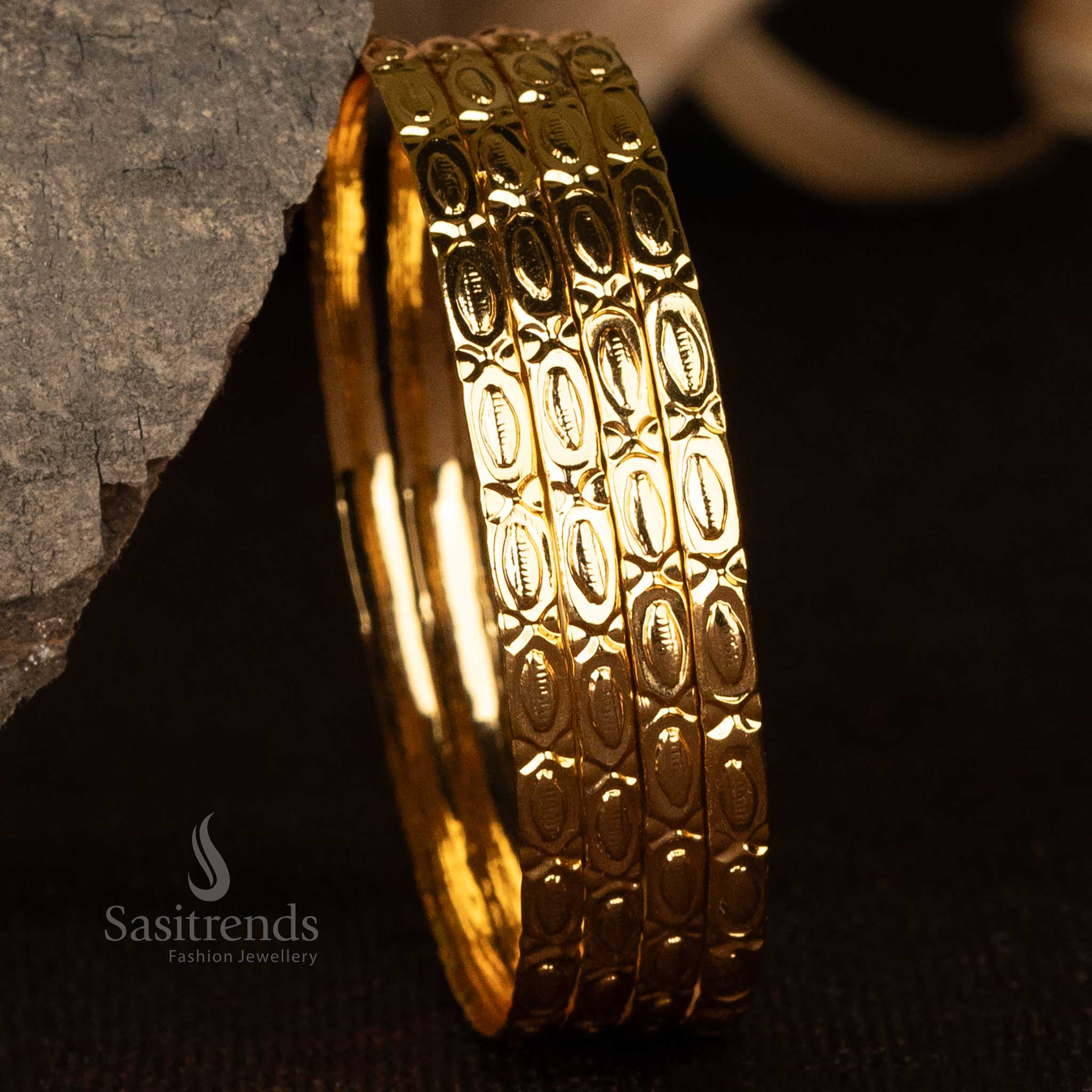 Gold-plated bangles featuring intricate oval engravings and a polished finish - Sasitrends