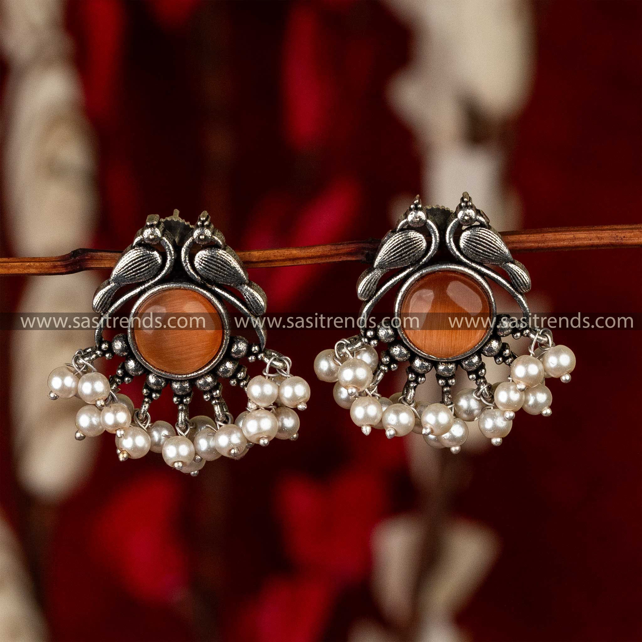 Oxidised earrings in a peacock design with burgundy stones and a trim of pearls