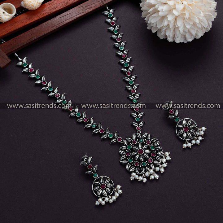 Trendy ruby-green stones adorn this classic Oxidised German Silver necklace with pearl earrings