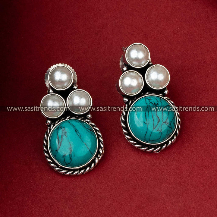 Oxidized silver earrings with a turquoise monalisa stone offering a pop of color, flanked by pearls for a classic look