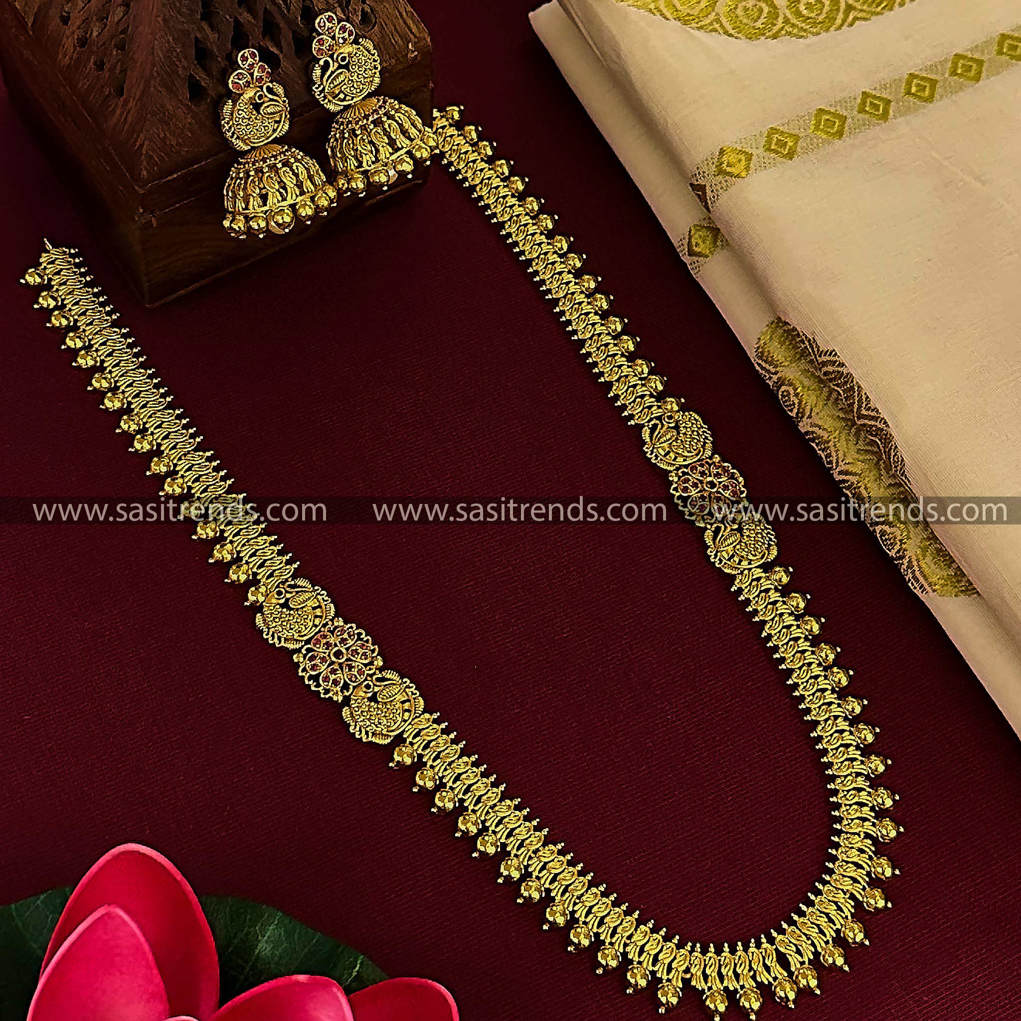 Matte gold plated long ruby necklace set with peacock motifs and matching jhumkas for women.