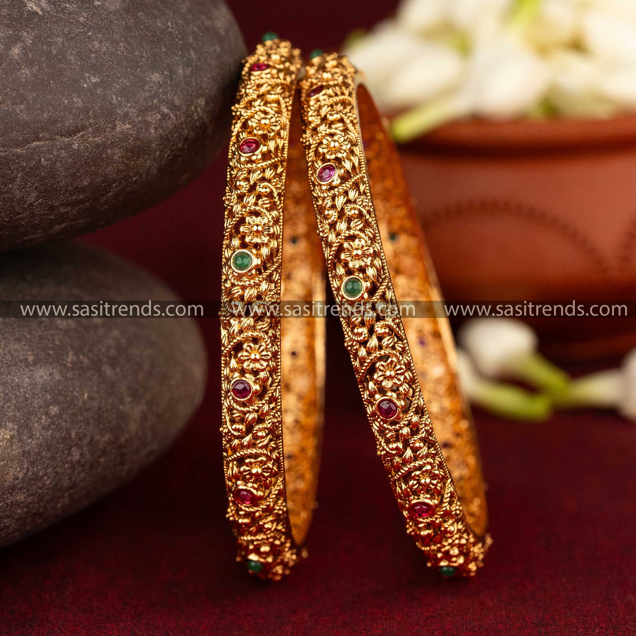 Antique matte gold bangles with intricate floral motifs and green AD stones