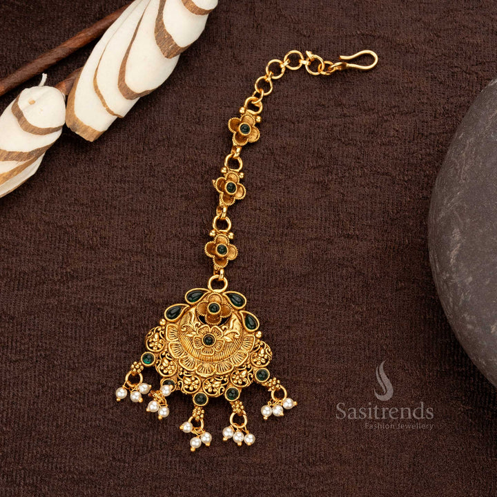 Matte gold floral maang tikka with synthetic green stones and pearl embellishments - Sasitrends