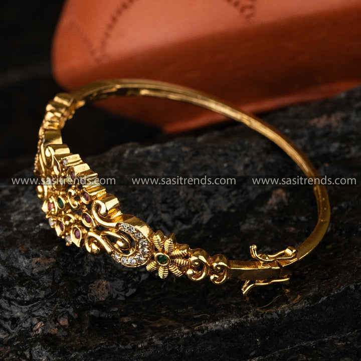 Elegant matte gold-plated temple bangle with multicolor American diamond embellishments, a sophisticated choice for cultural celebrations.