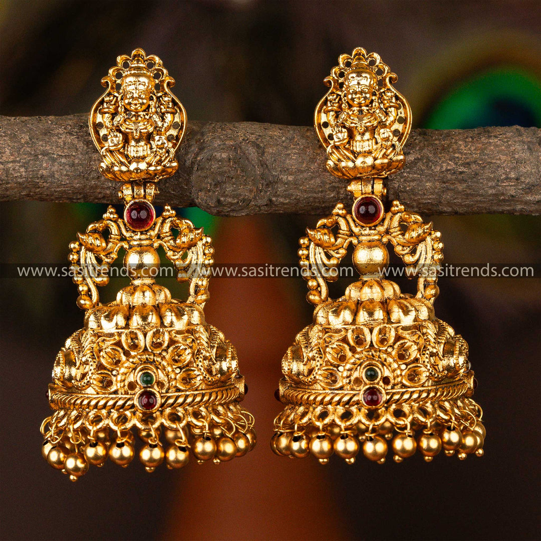 Bridal gold-plated temple jhumka earrings featuring peacock motifs and ruby embellishments, a testament to Indian artisanal heritage