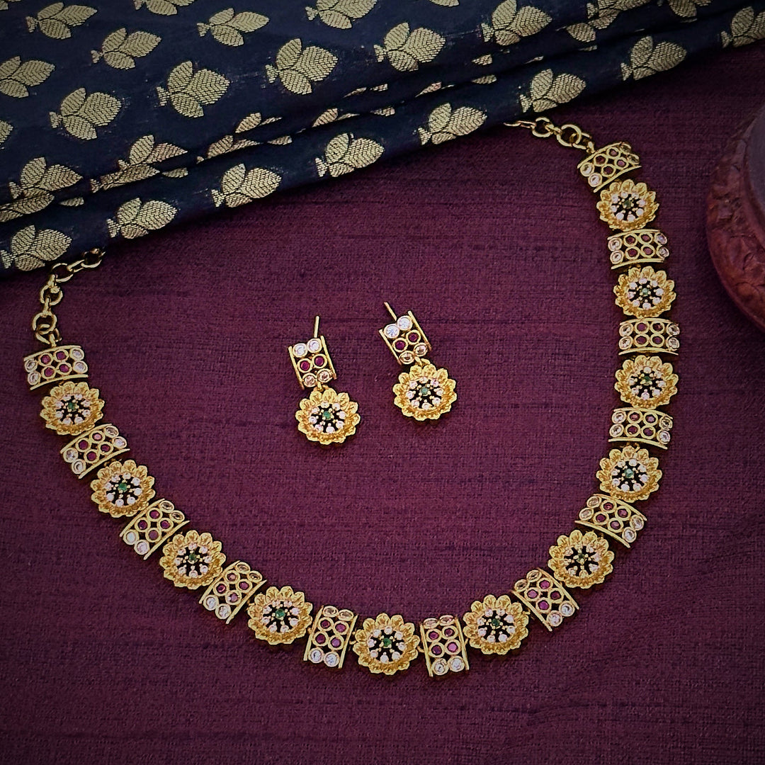 Close-up of Short Necklace Set with Floral and Rectangular Patterns: Featuring Emerald Green, Ruby, and American Diamond Stones on Matte Gold Finish.